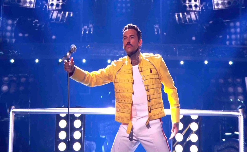 a man in a yellow jacket is singing into a microphone