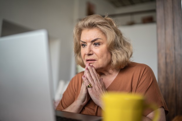 a woman is looking at a laptop with her hands on her face