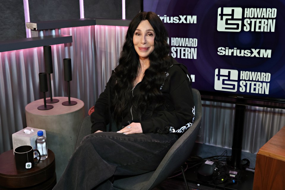 a woman sits in front of a howard stern sign