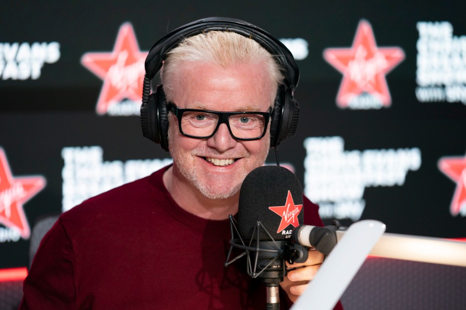 a man wearing headphones and glasses stands in front of a virgin radio microphone