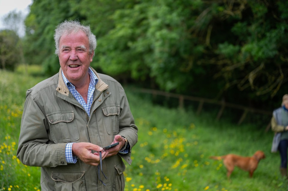 a man standing in a field with a dog behind him