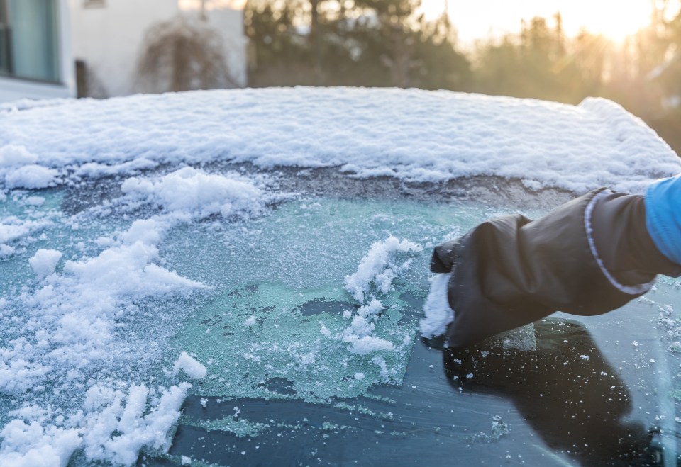 a person is cleaning the windshield of a car from snow