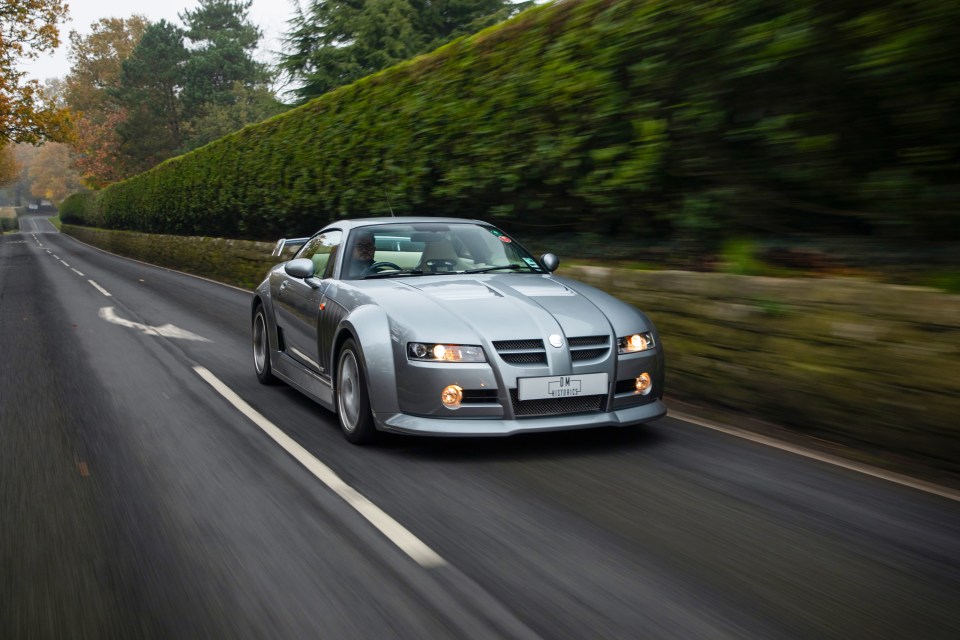 a silver sports car is driving down a road