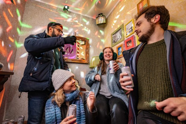 a group of people are sitting in a room drinking beer