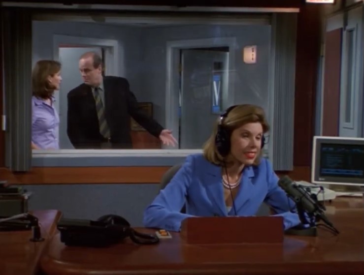 a woman wearing headphones sits at a desk in front of a microphone