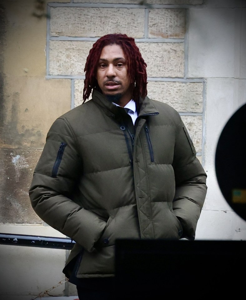 a man with red dreadlocks is wearing a green jacket