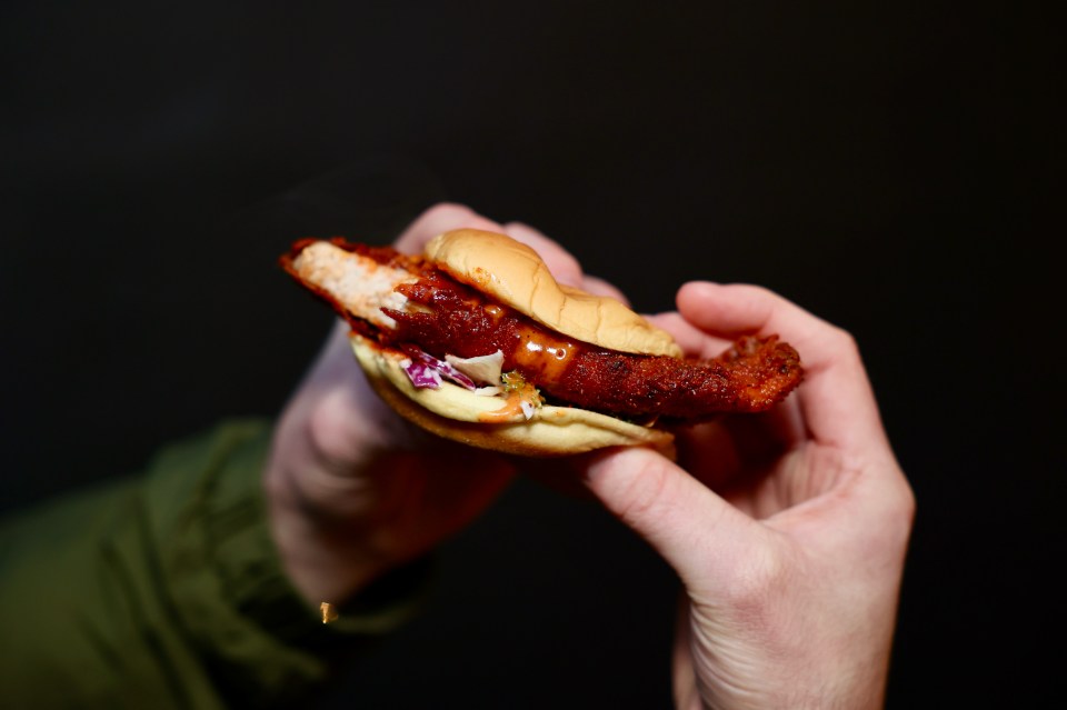 a person is holding a chicken sandwich in their hands