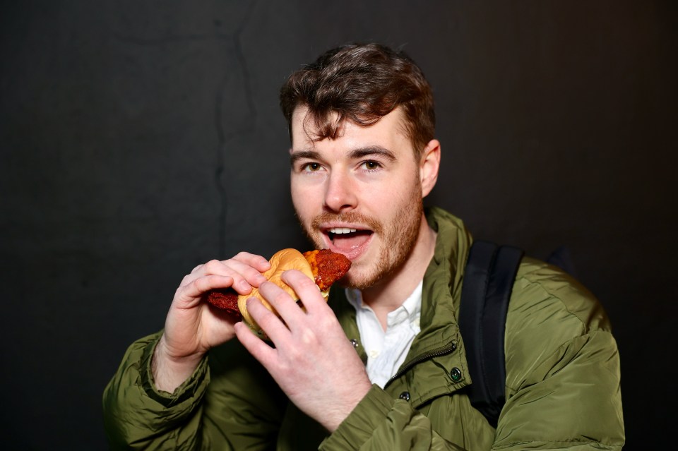 a man in a green jacket is eating a sandwich