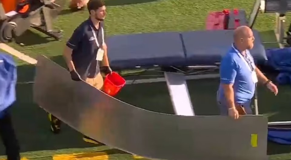 two men are carrying a large piece of metal on a field .