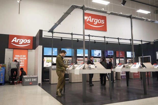 a man stands in front of a sign that says argos