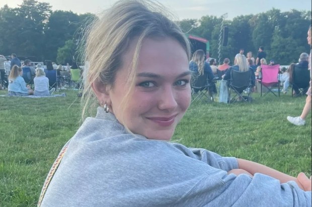 a woman sits in the grass with her legs crossed