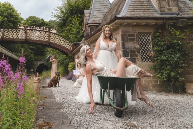 a bride and her bridesmaid are pushing a wheelbarrow in front of a castle