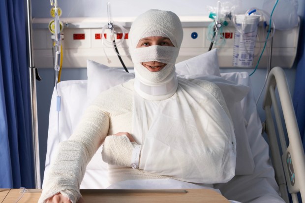 a man with a bandaged head and arm is sitting in a hospital bed