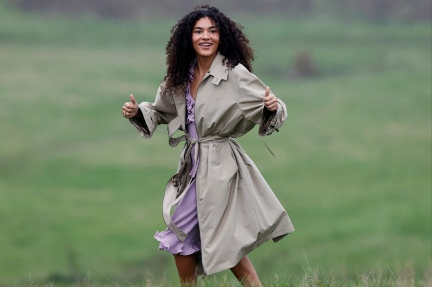 a woman in a trench coat giving a thumbs up