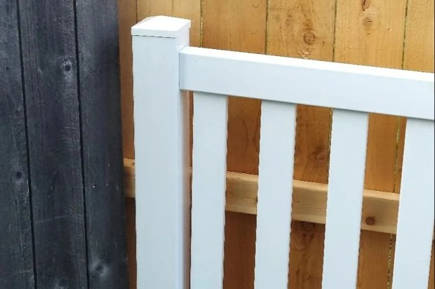 a white railing is next to a wooden fence