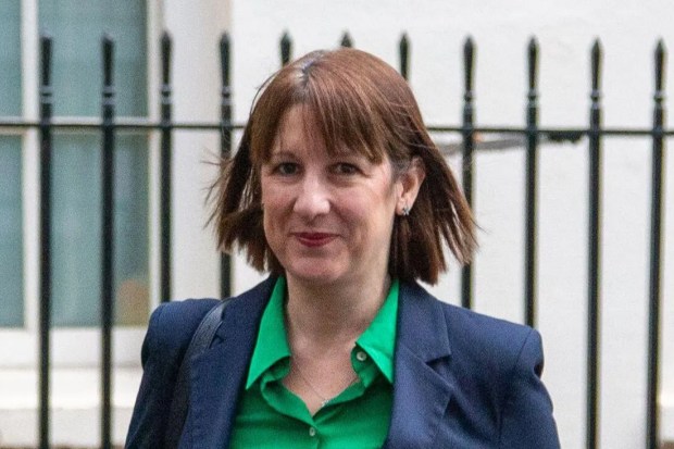 a woman in a suit and green shirt is walking down the street