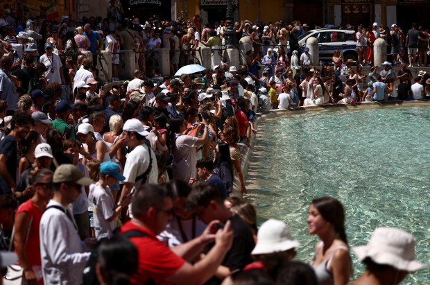 a crowd of people are gathered around a fountain in front of a gelateria