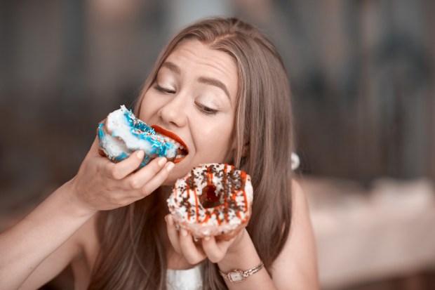 a woman is eating a donut with blue and white sprinkles