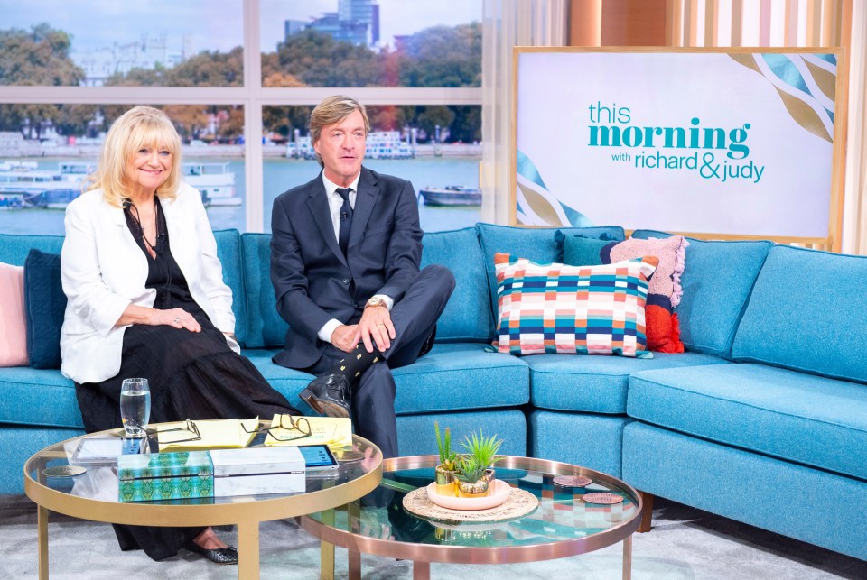 two people sit on a couch in front of a sign that says this morning with richard and judy