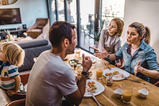 a family sits at a table with plates of food and talking