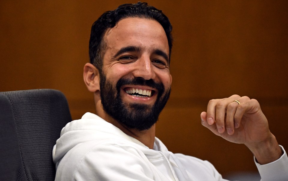 a man with a beard wearing a white hoodie is smiling