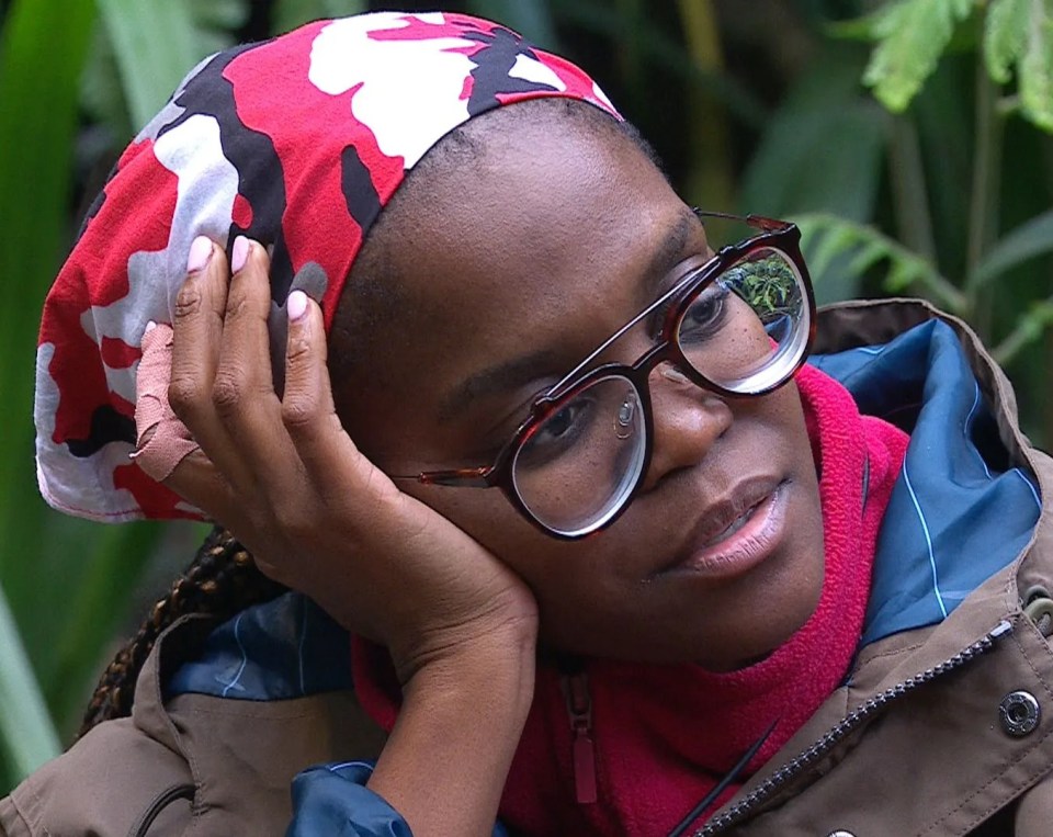 a woman wearing glasses and a headband rests her head on her hand