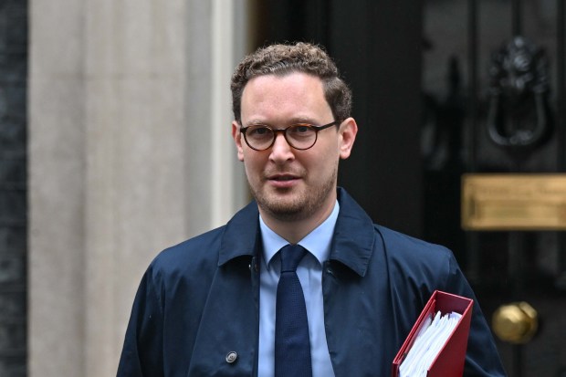 a man in a suit and tie is holding a red folder