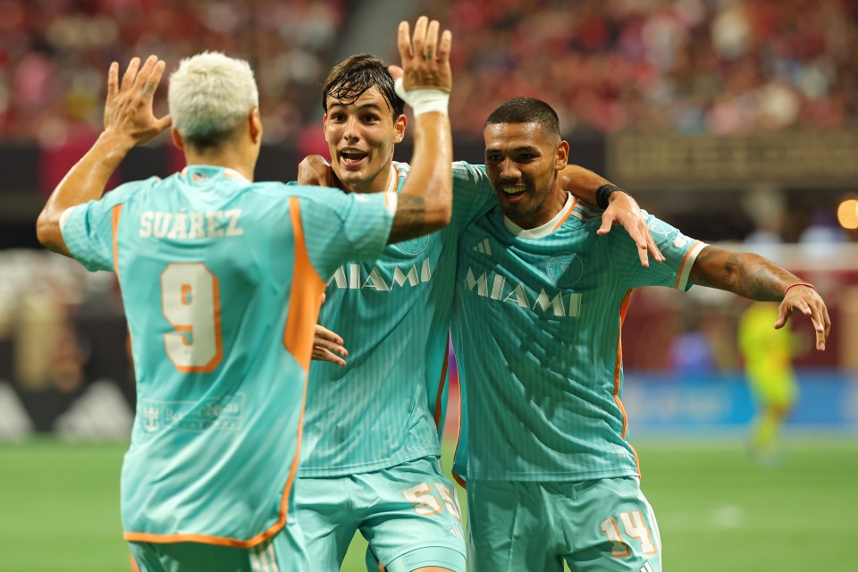 three miami soccer players high five each other on the field