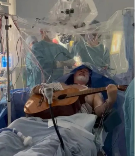 Patient Colin Miller plays the guitar during his brain surgery