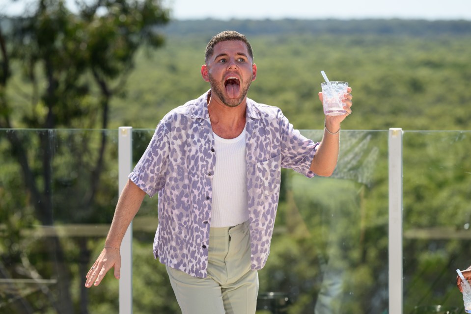 a man in a leopard print shirt is sticking his tongue out while holding a drink