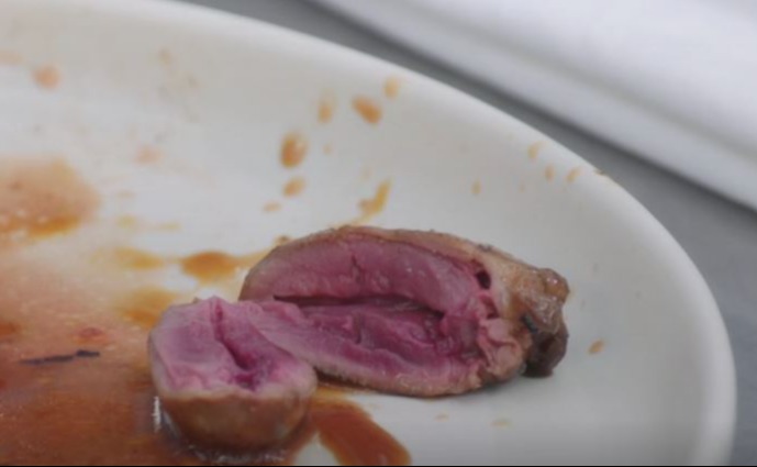 a piece of meat on a white plate with bbc written on the bottom