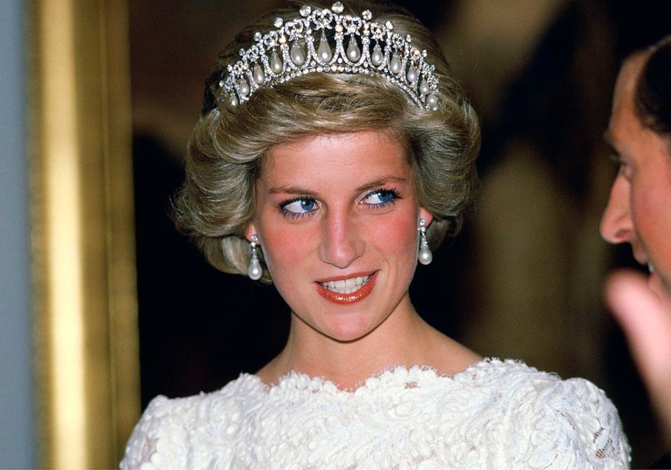 a woman wearing a tiara and earrings smiles for the camera