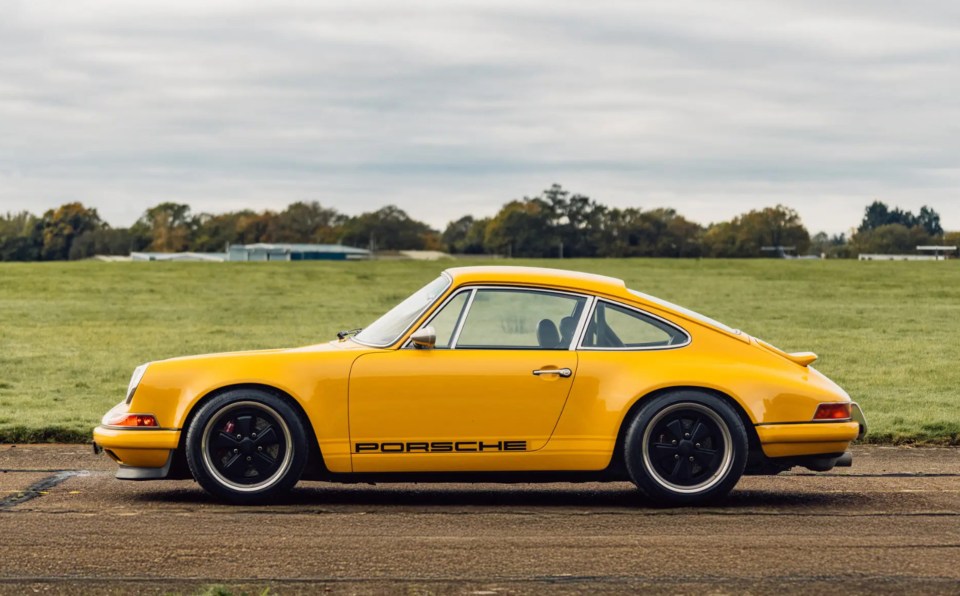 a yellow porsche is parked in a grassy field