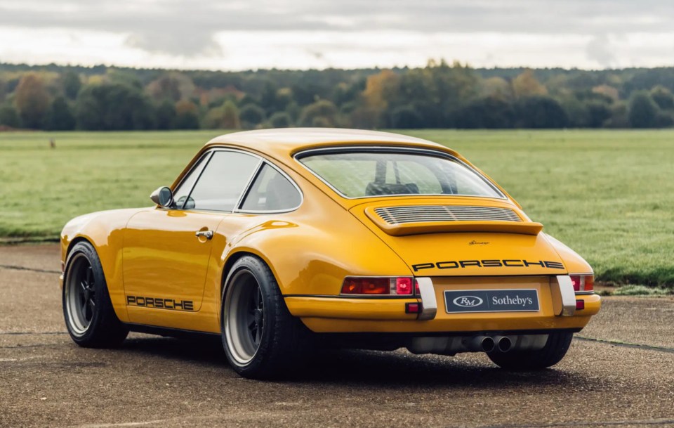 a yellow porsche is parked in a field