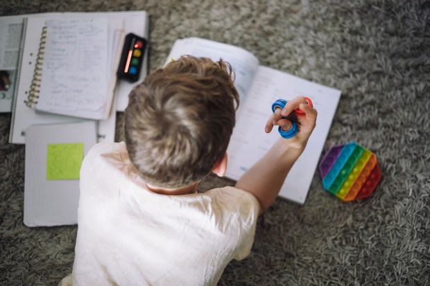 a boy is playing with a fidget toy while doing his homework