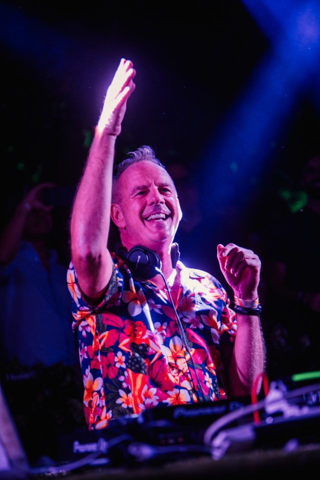 a man in a floral shirt is wearing headphones and smiling