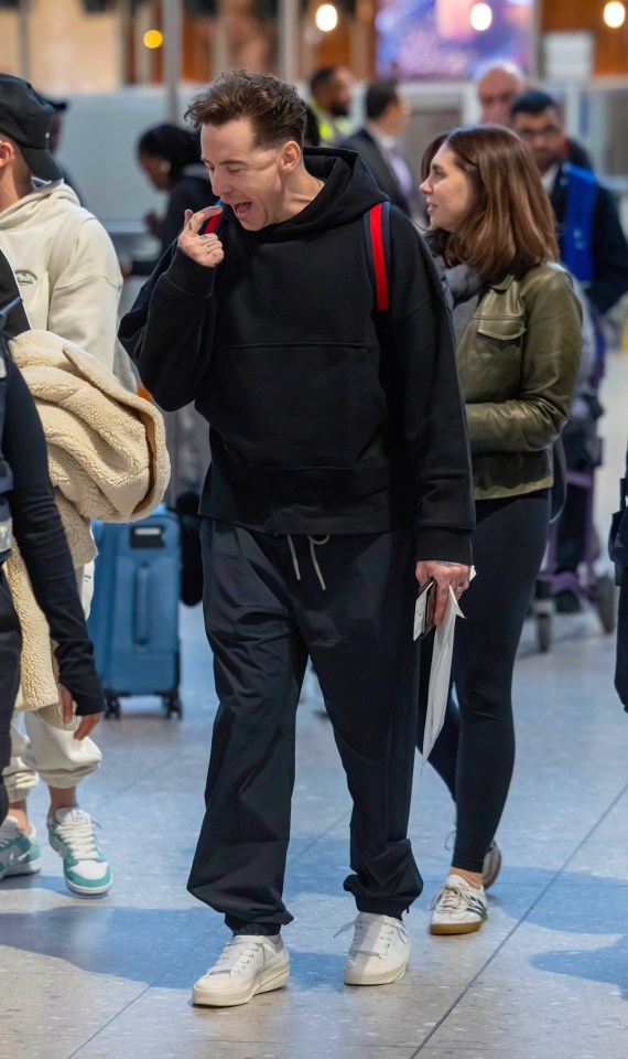 a man in a black hoodie is walking with a woman in a green jacket