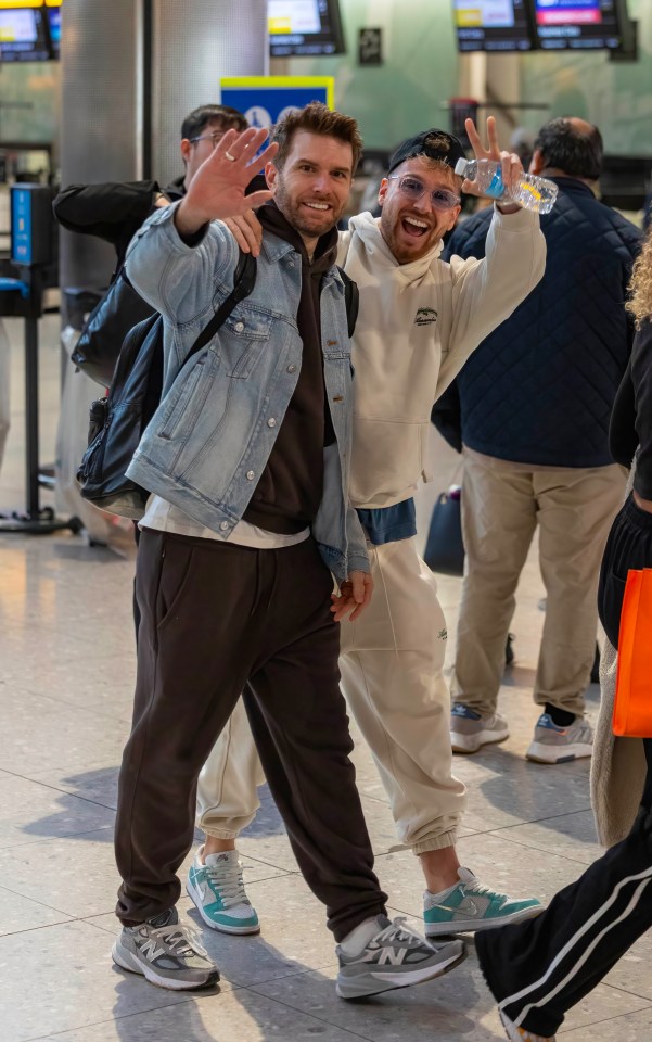 a man holding a bottle of water stands next to another man