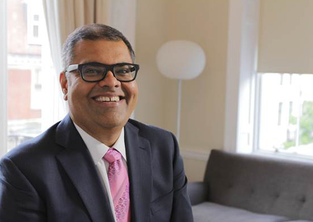 a man in a suit and tie is smiling while sitting on a couch .