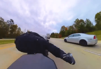 a person is riding a motorcycle on a highway with a silver car behind them