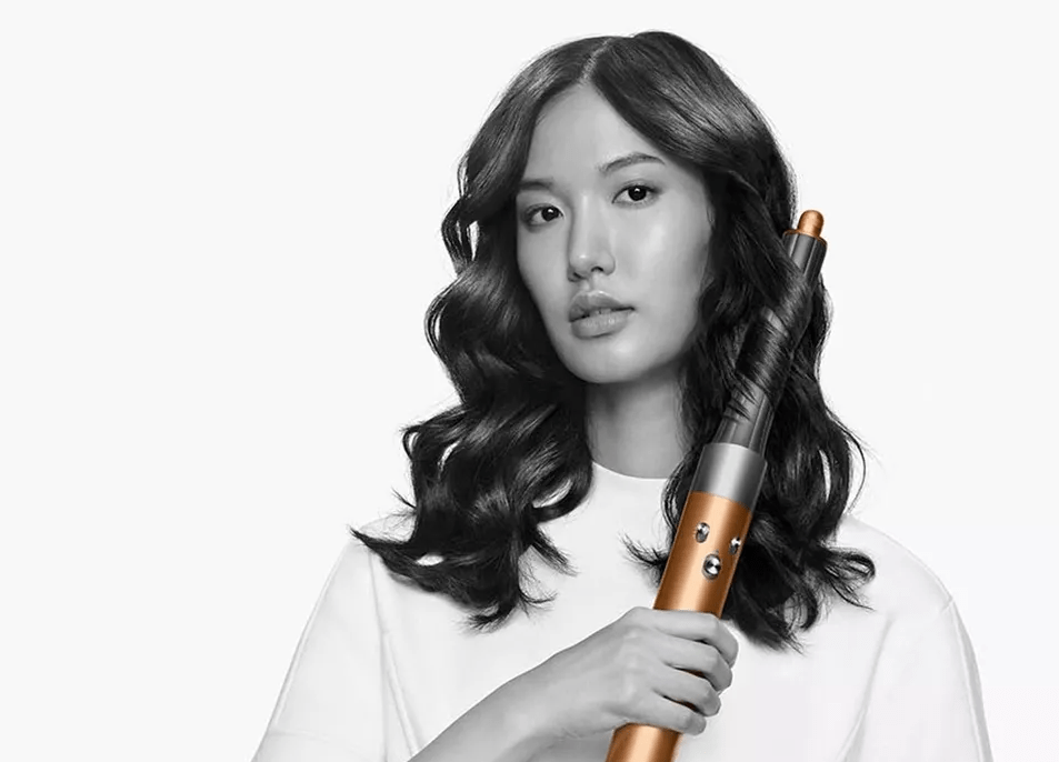 a woman in a white shirt is holding a hair curler