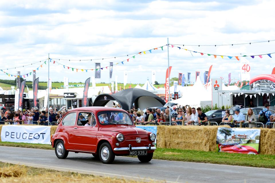 a red peugeot car is driving down a road