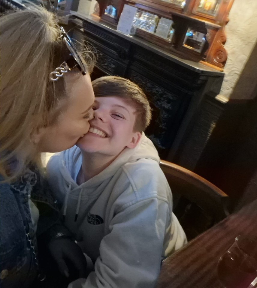 A woman kissing a younger person on the cheek.