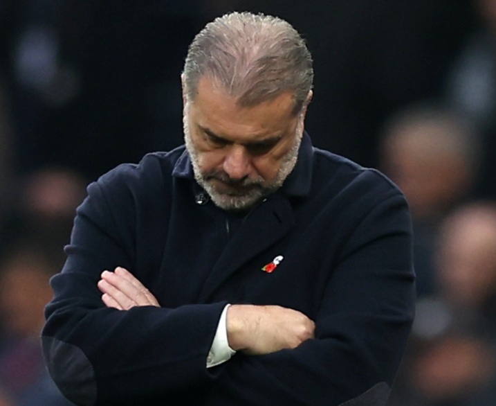 a man in a black coat has a red poppy on his shirt