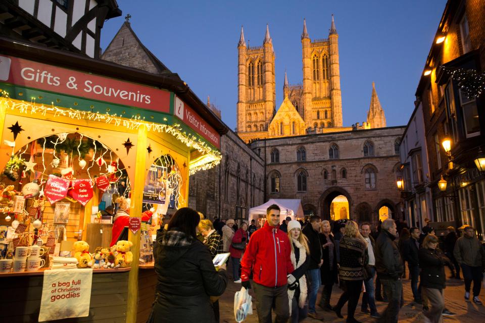 a group of people walking past a gifts and souvenirs stand