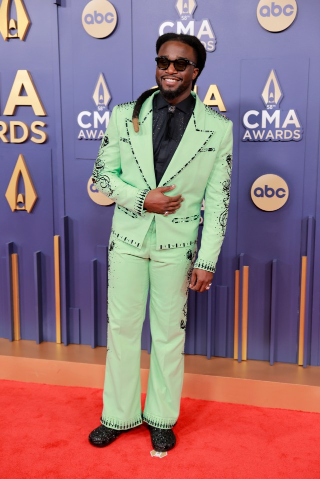 a man in a green suit is on the red carpet at the cma awards