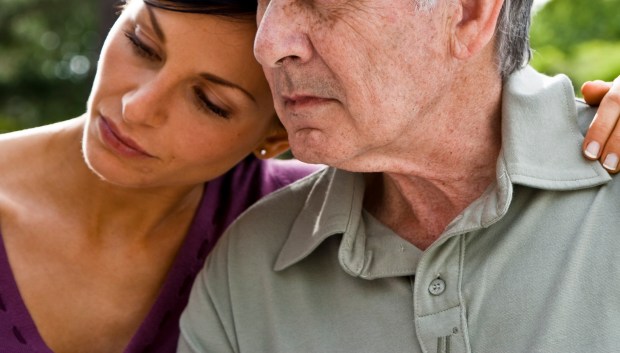 a woman leans her head on an older man 's shoulder