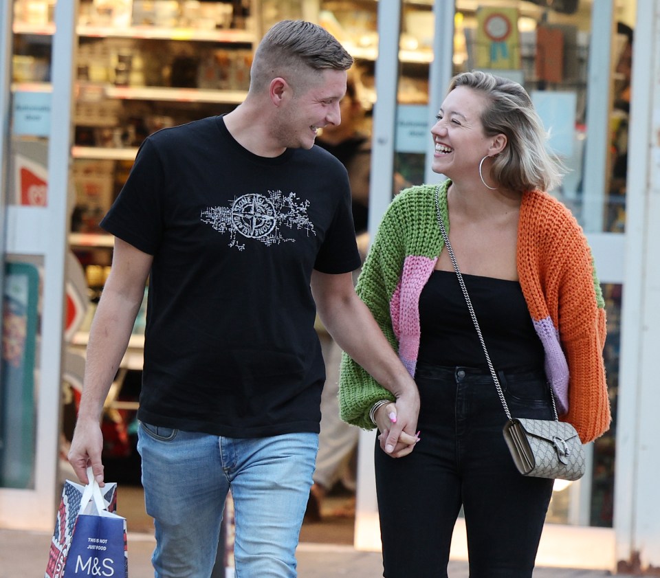 a man wearing a black shirt with a compass on it holds hands with a woman