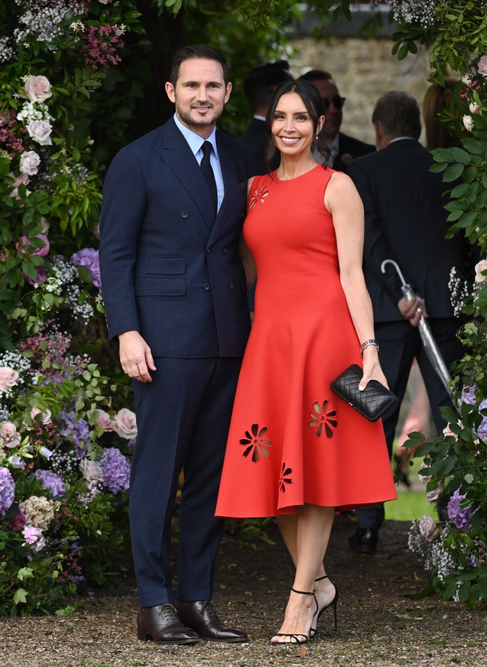 a man in a suit and tie stands next to a woman in a red dress