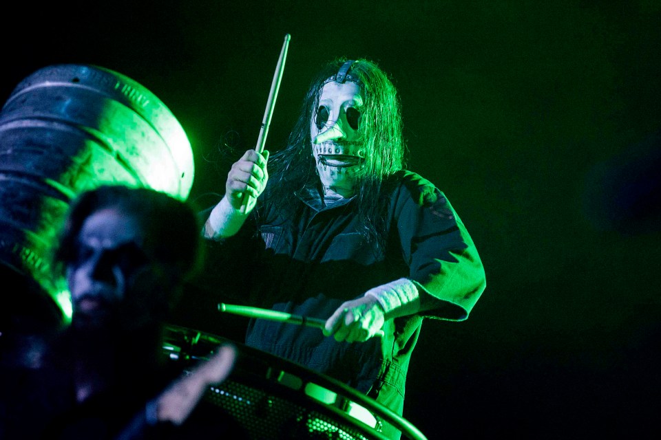 a man in a mask is holding a drum stick